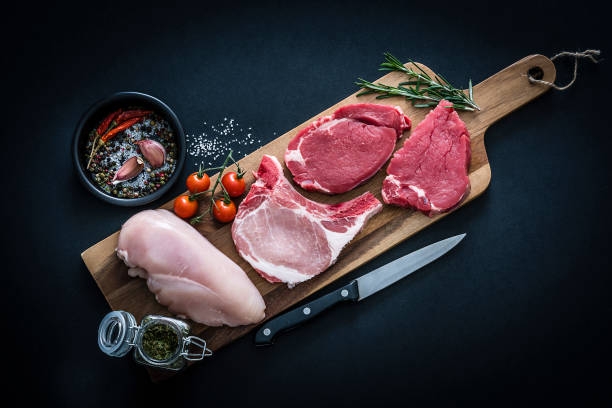 Thịt bò, sườn heo và ức gà tươi bày trên thớt gỗ