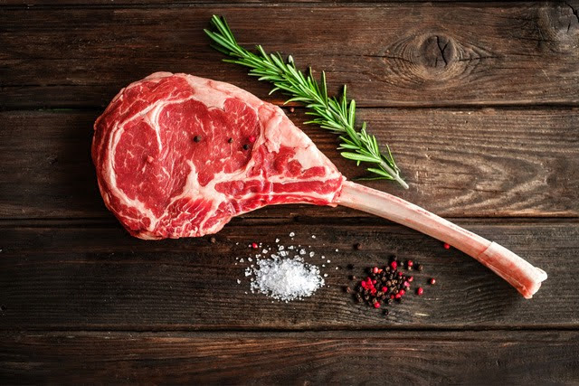 Miếng bò Tomahawk nguyên xương trên nền gỗ